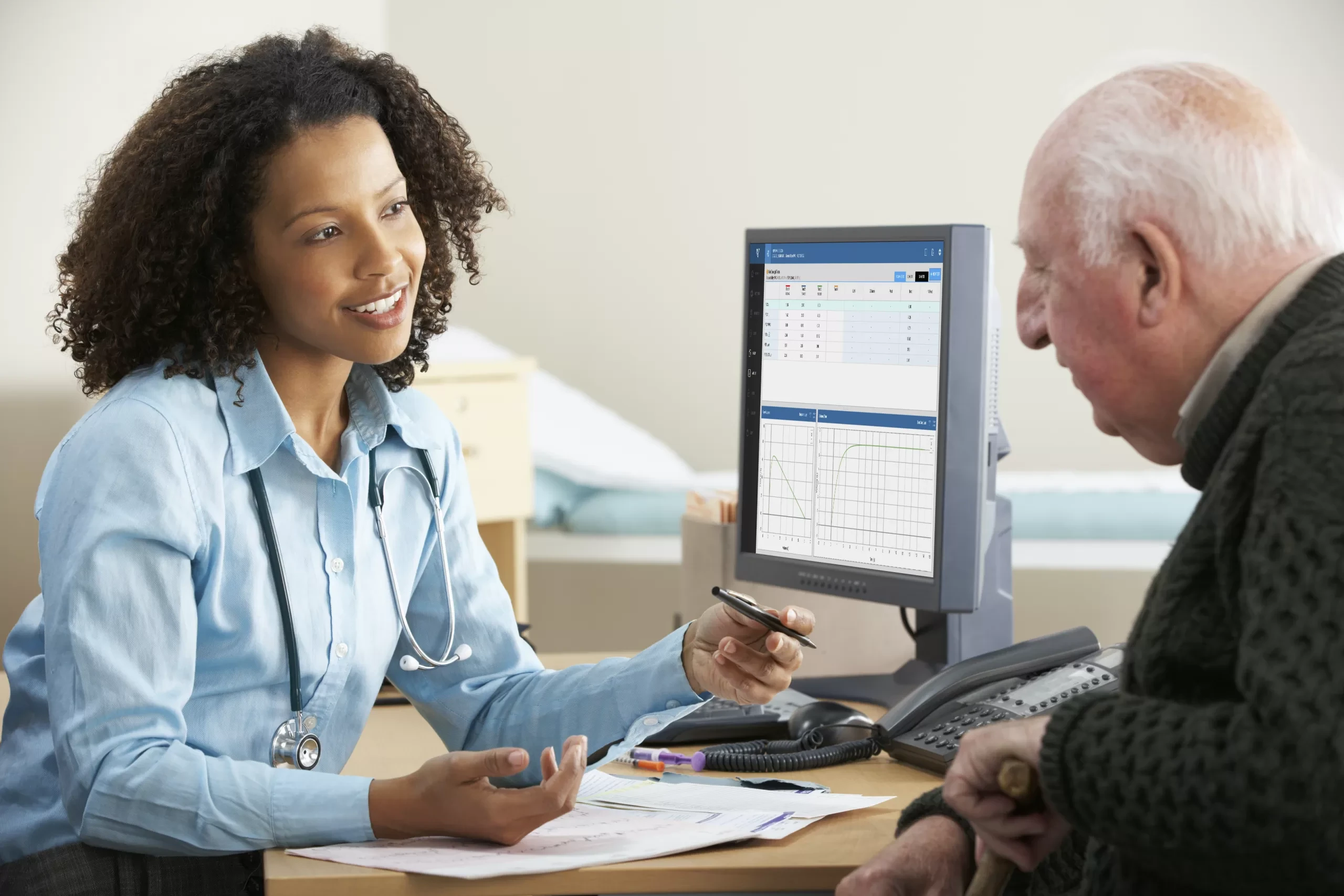Ärztin mit Stethoskop sitzt einem älteren Mann gegenüber und bespricht die Patientenakte.